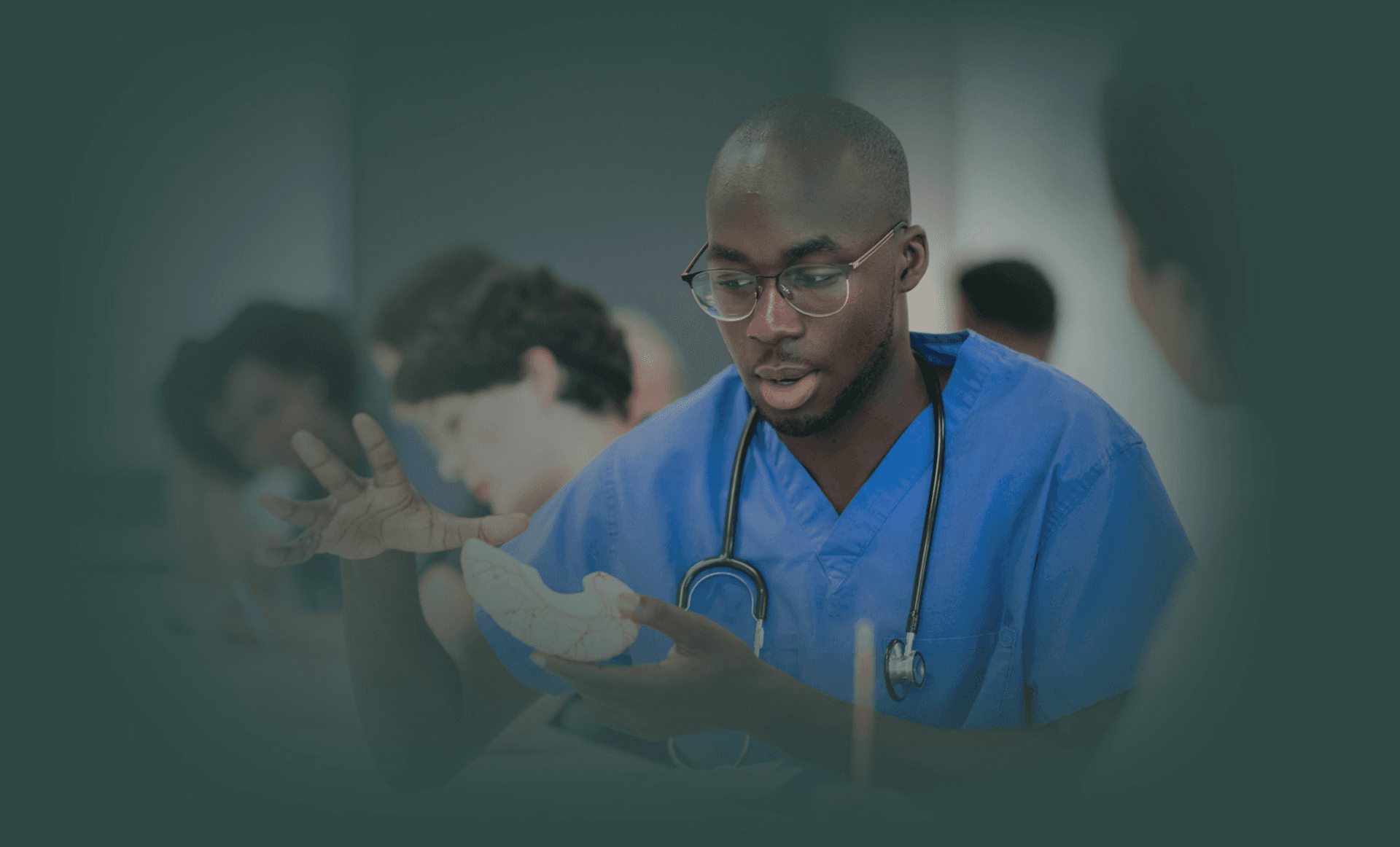 A Black medical student sitting in a classroom with other students.